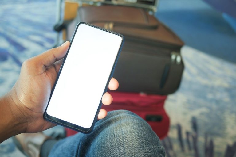 Ecossistema brasileiro de tecnologia para viagens chega a 225 soluções mapeadas Pessoa segura um smartphone em um aeroporto, com bagagem visível ao fundo.