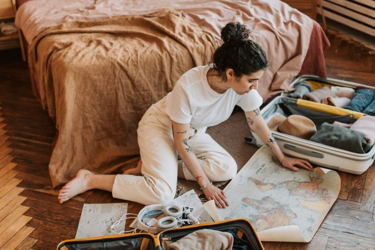 Booking.com prevê viagens guiadas por humor, orçamento e inteligência artificial em 2027 Mulher planeja uma rota de viagem em um quarto, cercada por malas e um mapa.
