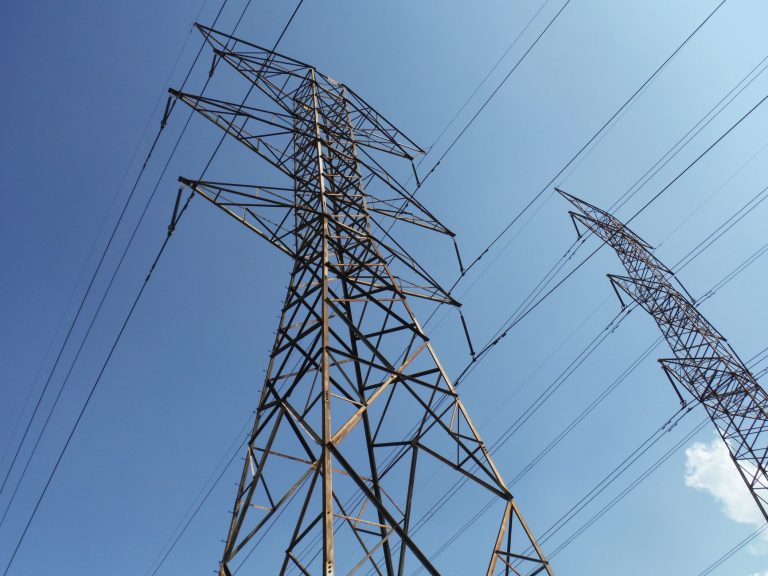 Senado dos EUA prepara votação sobre custos de data centers na conta de luz Torres e linhas de transmissão de energia elétrica vistas de baixo contra um céu azul.